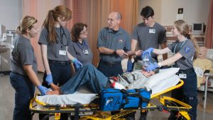 students and instructor working on medical dummy on a stretcher
